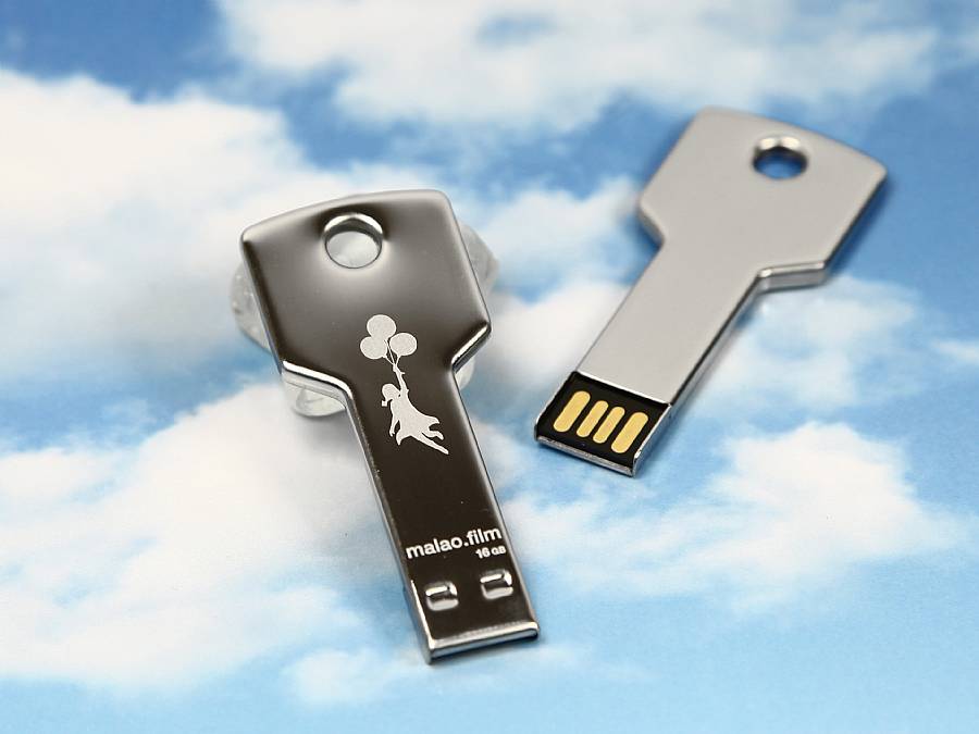 USB-Stick in Form eines Schlüssels mit silbernem Gehäuse und einem bedruckbaren Bereich für individuelles Branding.