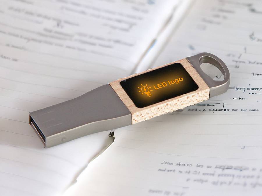 USB-Stick mit individuell bedruckbarem LED-Bereich und modernem, grauem Gehäuse auf einem Notizblatt.